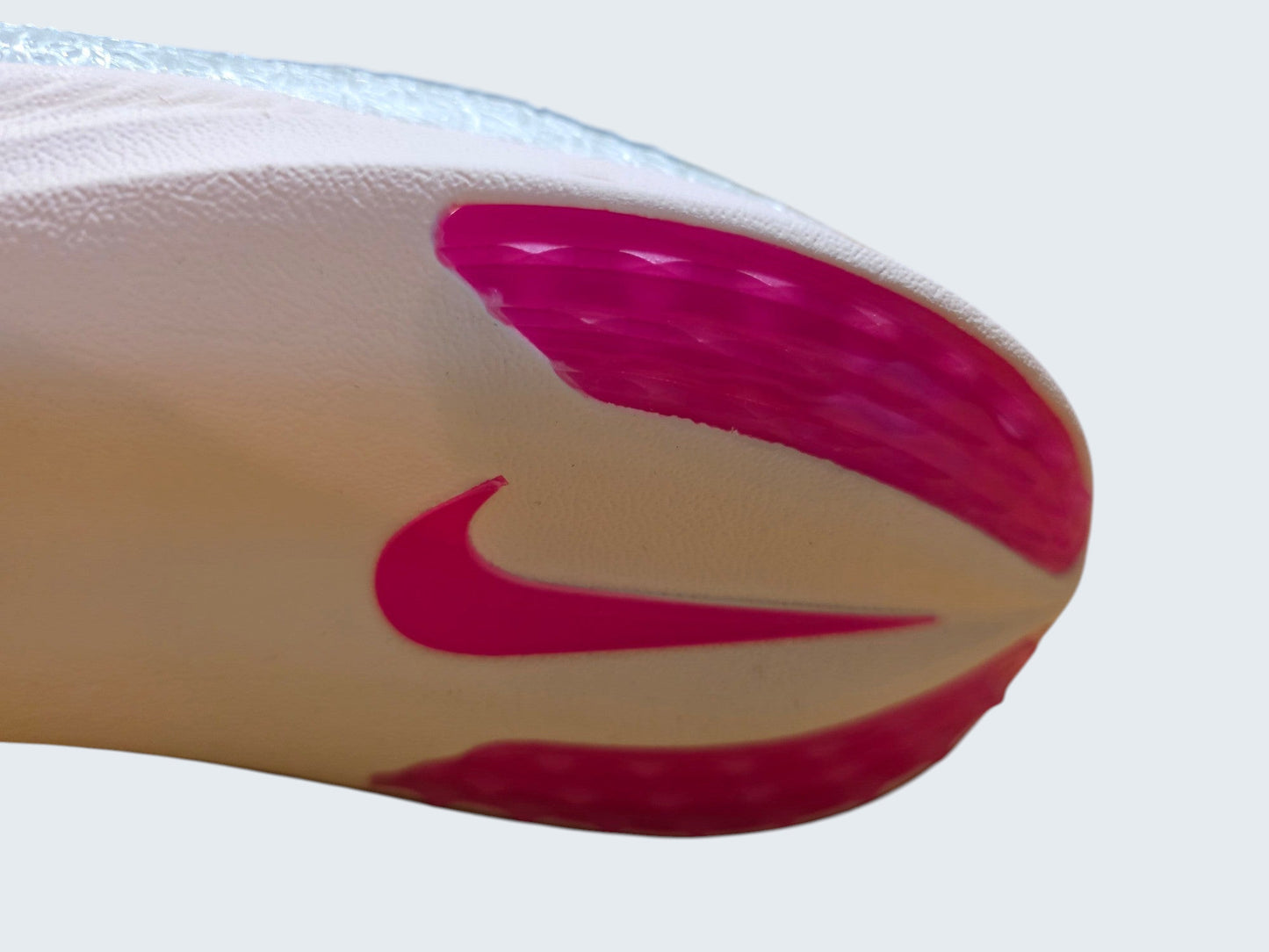 Zbliżenie na podeszwę butów lekkoatletycznych Latające Wieszaki Nike Air Zoom Victory w kolorze białym z różowym logo