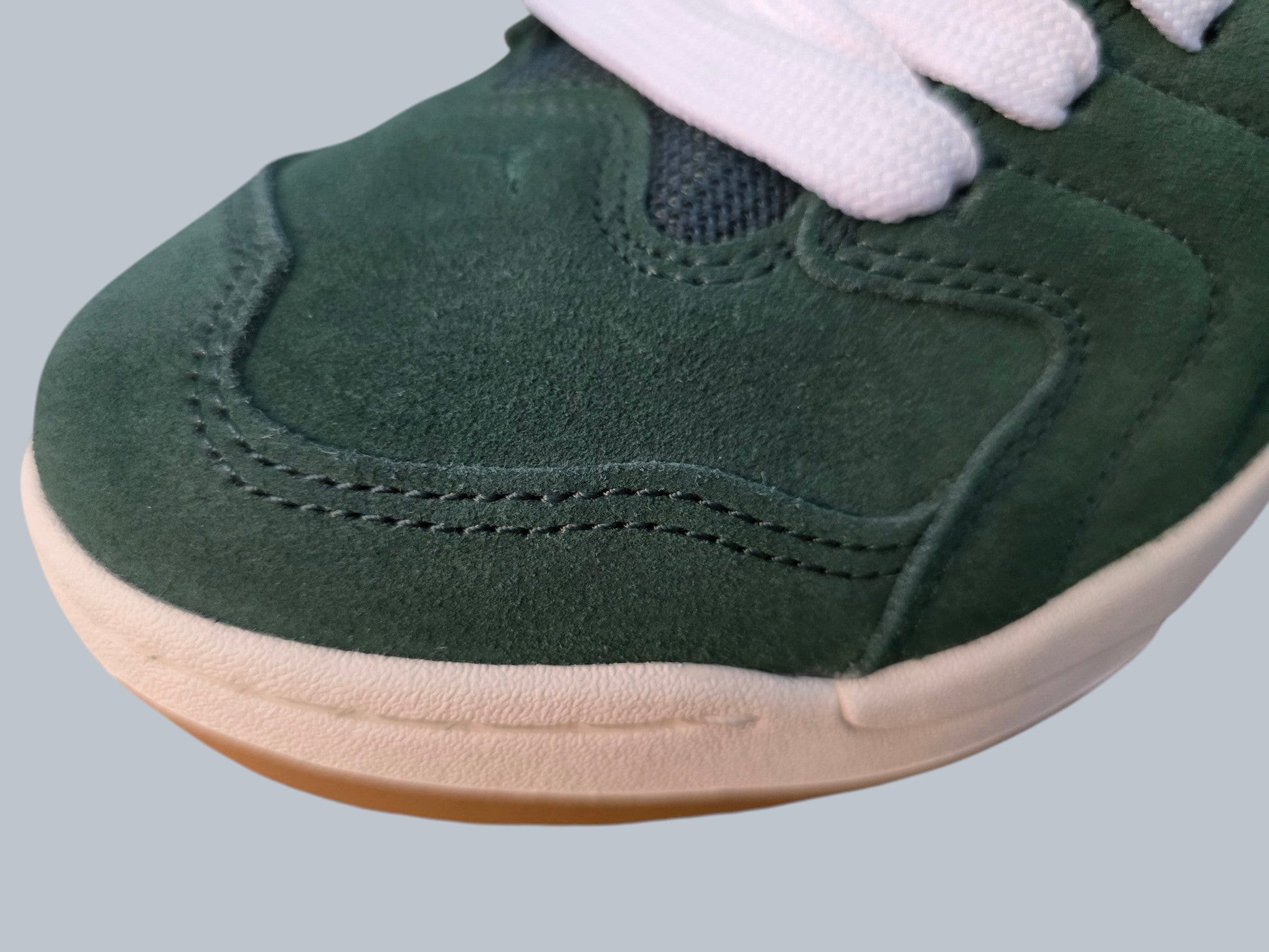 Zbliżenie na butelkowozielone zamszowe sneakersy Jordan Latające Wieszaki z białymi sznurowadłami i gumową podeszwą