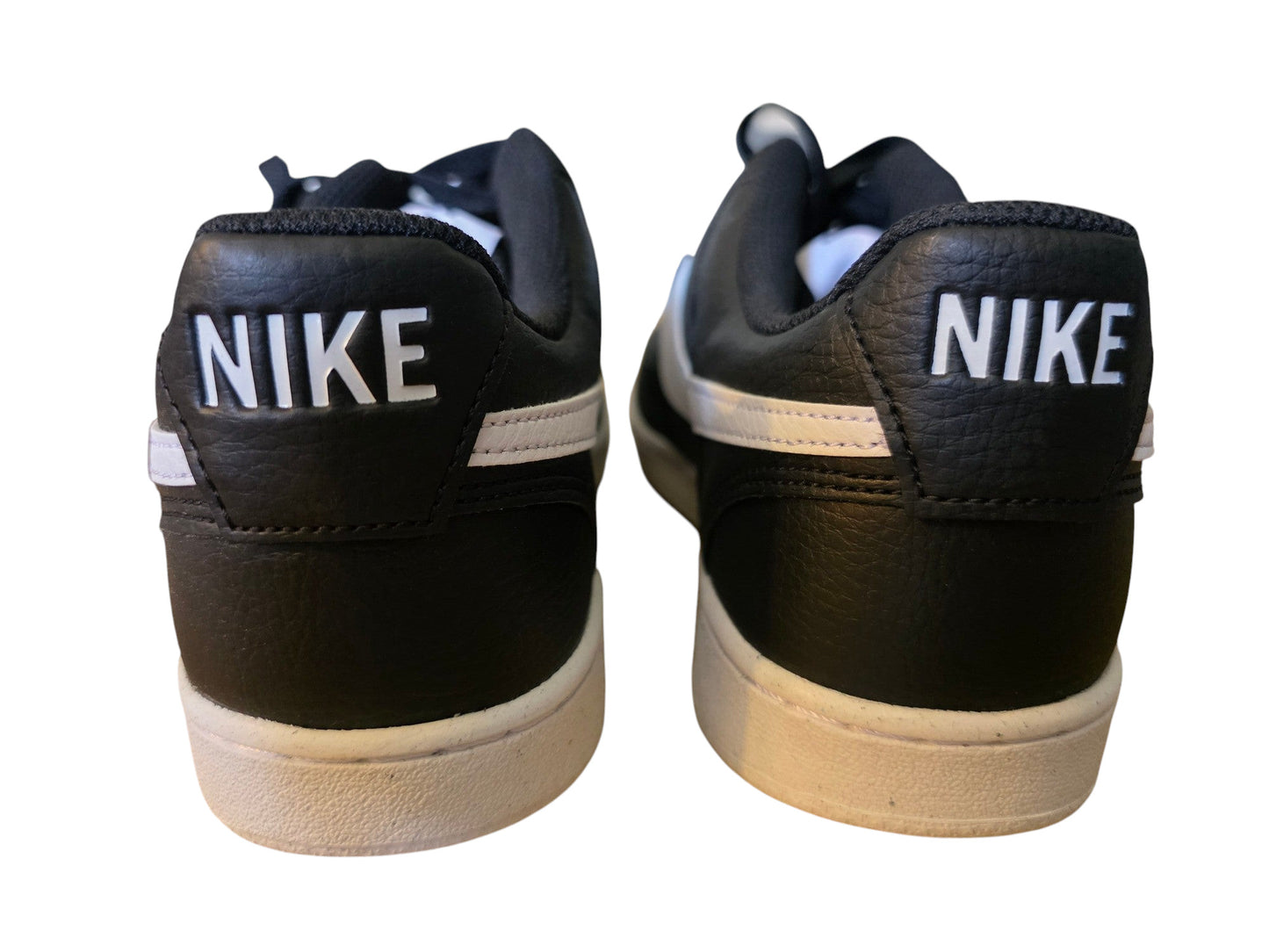 Tylny widok czarnych butów Nike Court Vision Low z białym napisem Nike na zapiętku, oferowanych przez Latające Wieszaki