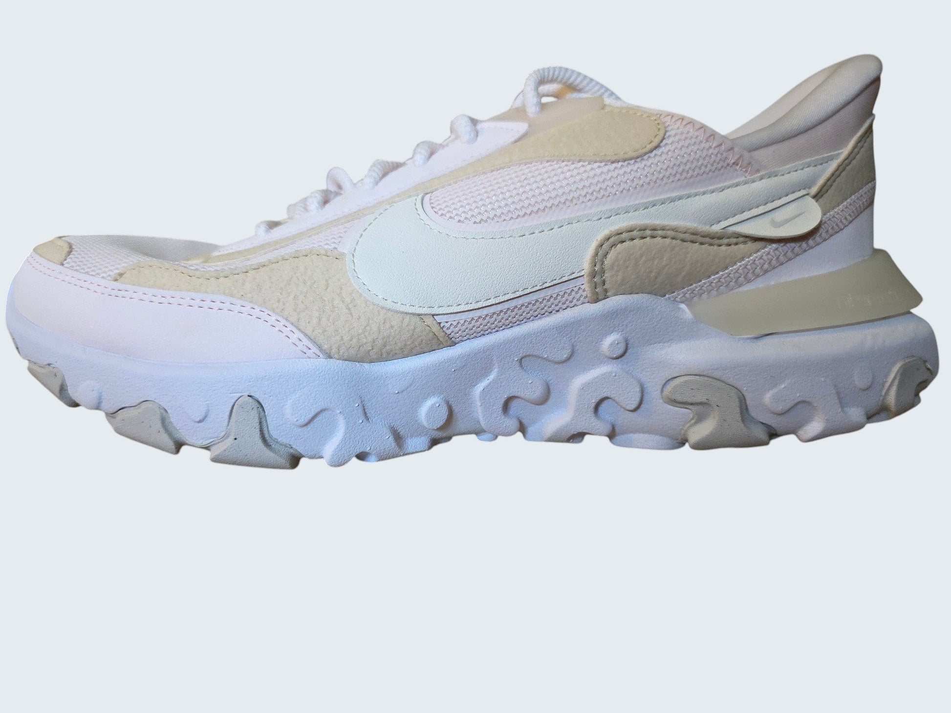 Damskie buty sportowe Latające Wieszaki Nike React Vision w pastelowych odcieniach różu, beżu i bieli na drewnianym stole